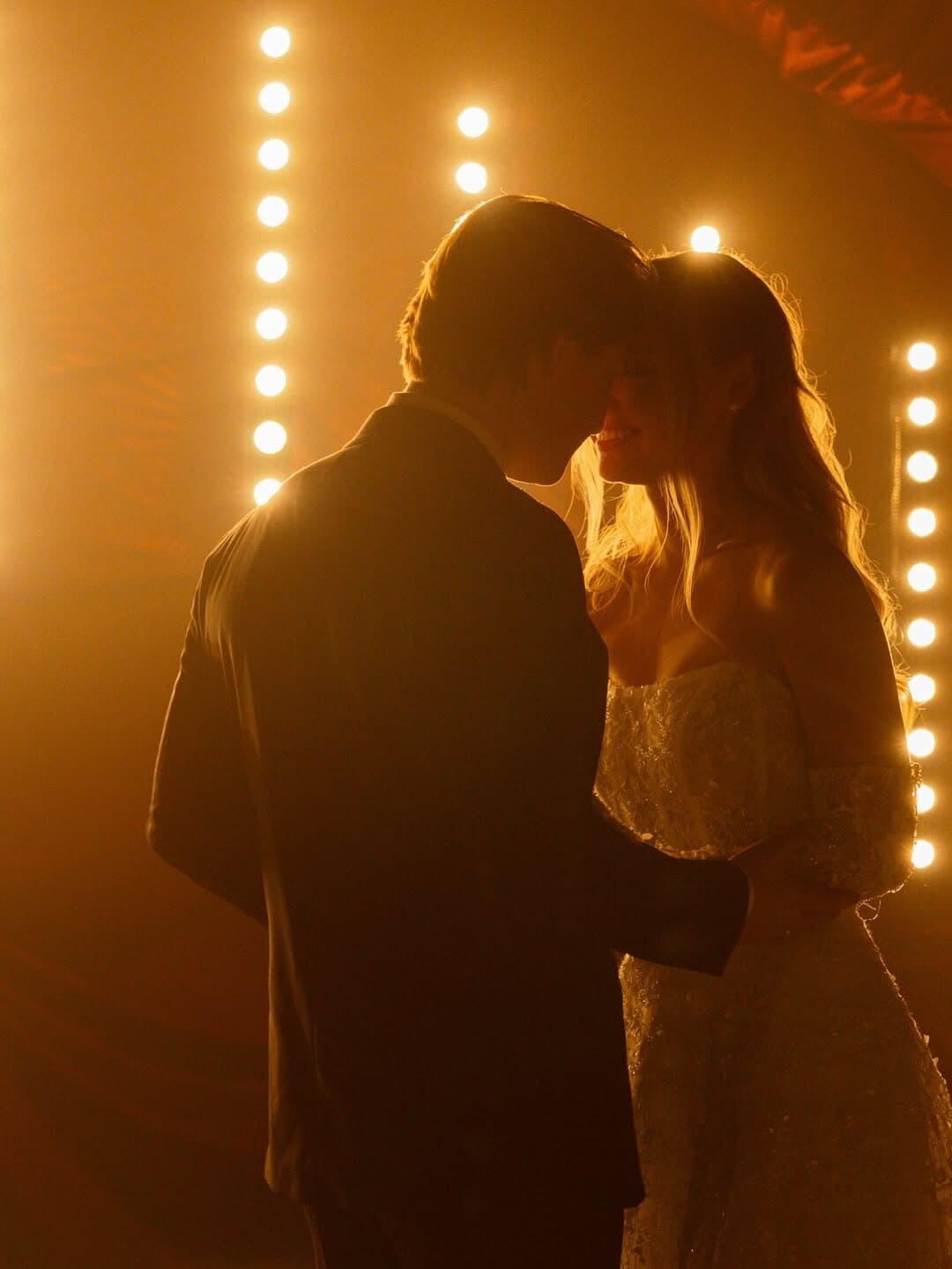 A couple held in the glow of warm bulb light